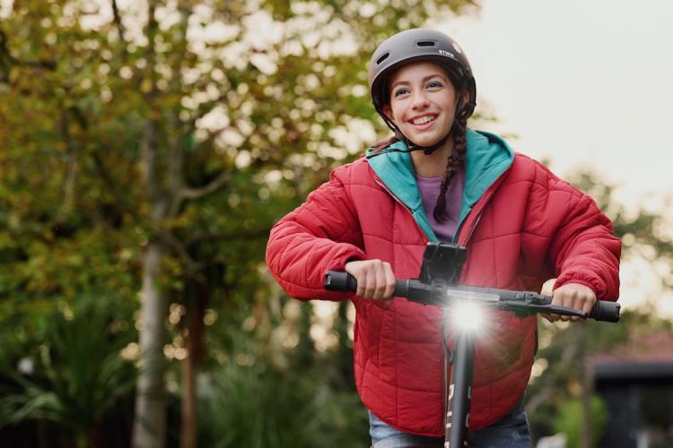 Flicka som k&ouml;r en elsparkcykel.